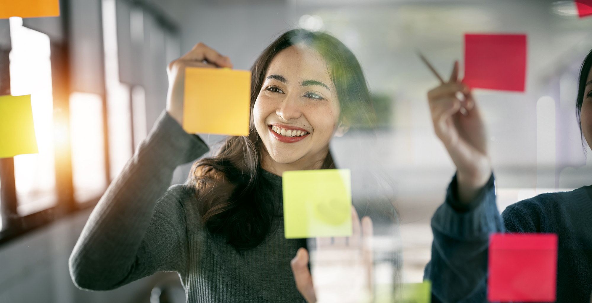 Image of people ideating with sticky notes on a window