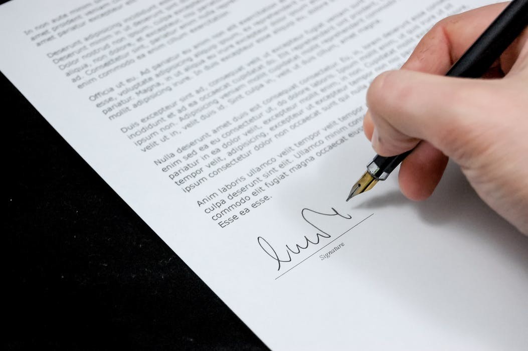 Image of a hand signing a cover letter