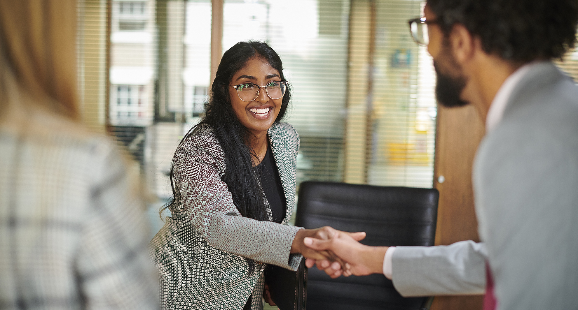 Image of young woman in a business suit shaking hands with prospective employer