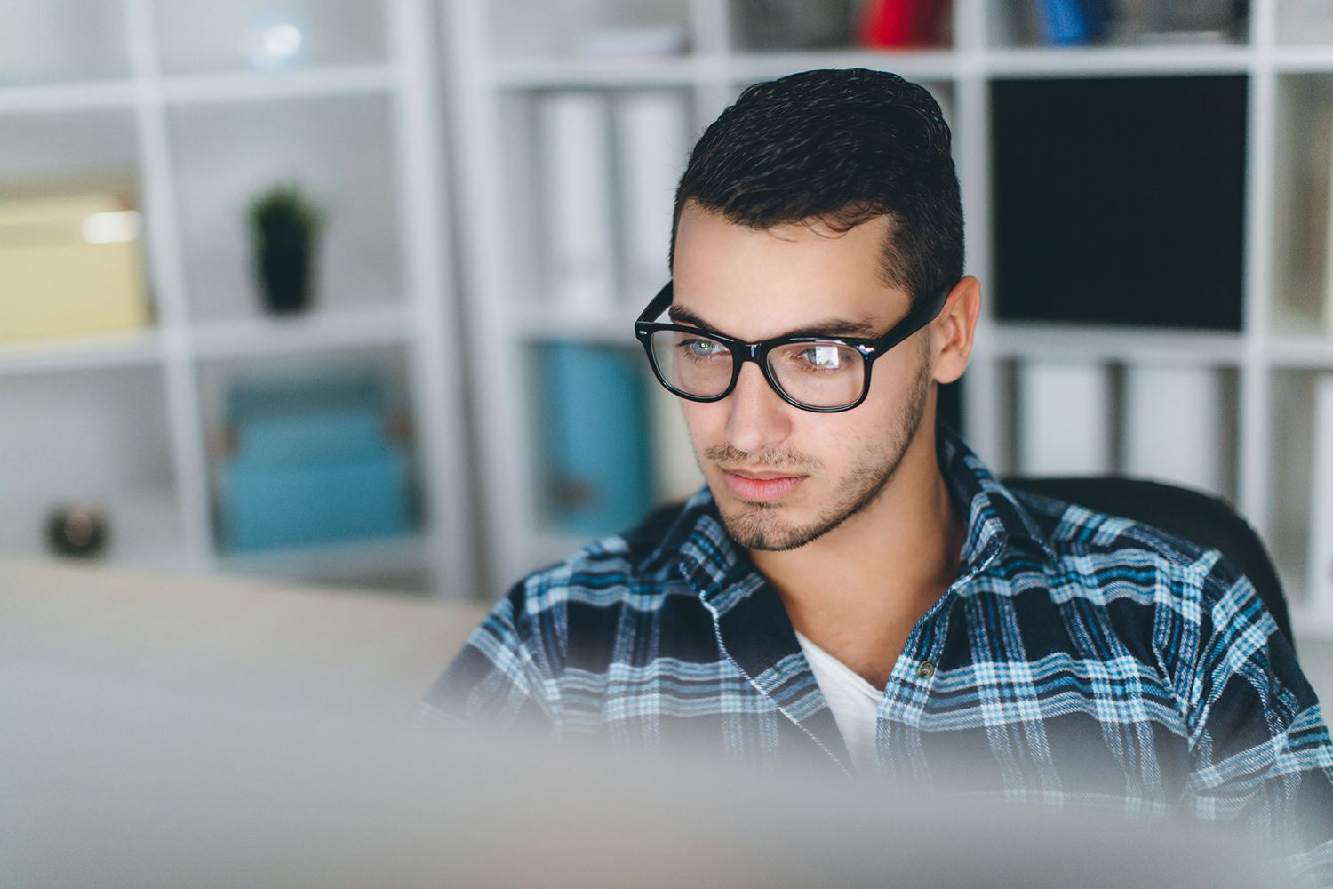 Image of man looking at computer with reflection on his glasses.