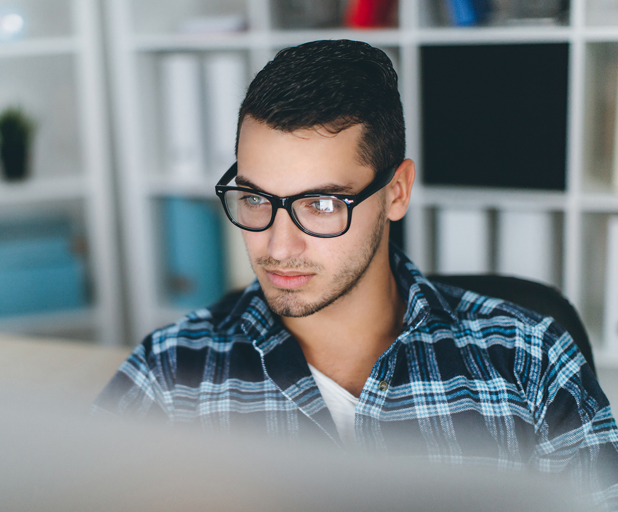 Image of man looking at computer with reflection on his glasses.