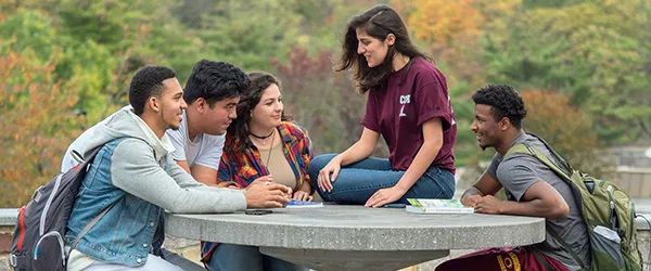 Image of a group of students sitting at a table outside
