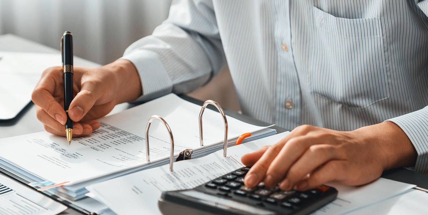 Man working with a calculator and spreadsheet.