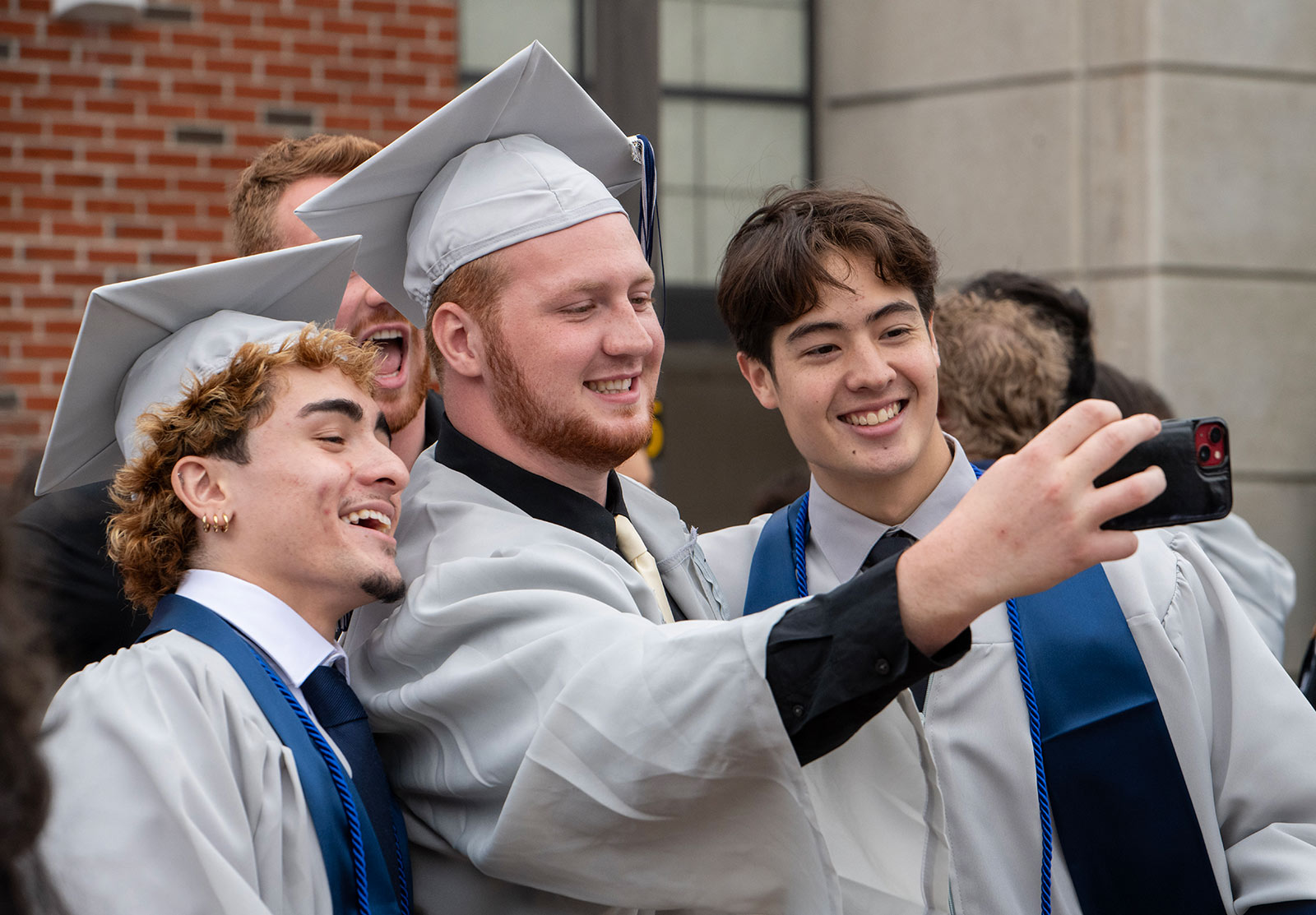 Three male students posing for a selfie after commencement