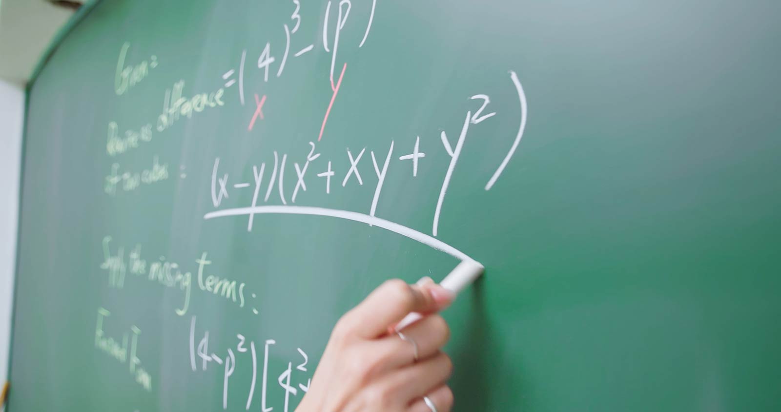Someone doing a math equation on a blackboard.